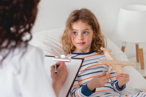 Girl holding a wooden plane talking to a nurse