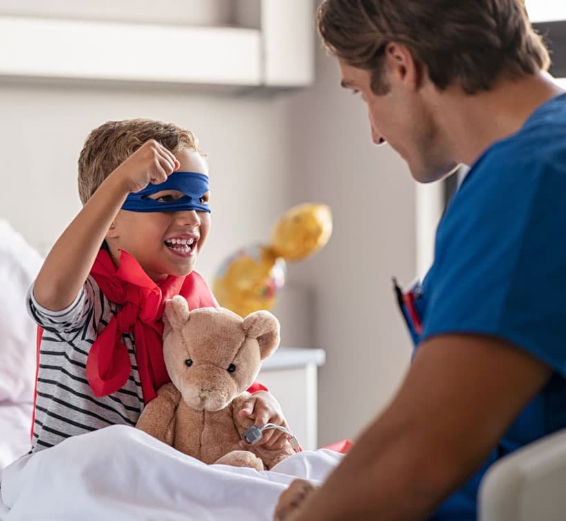 A child dressed up as zoro with a stuffed animal, a nurse holds his attention