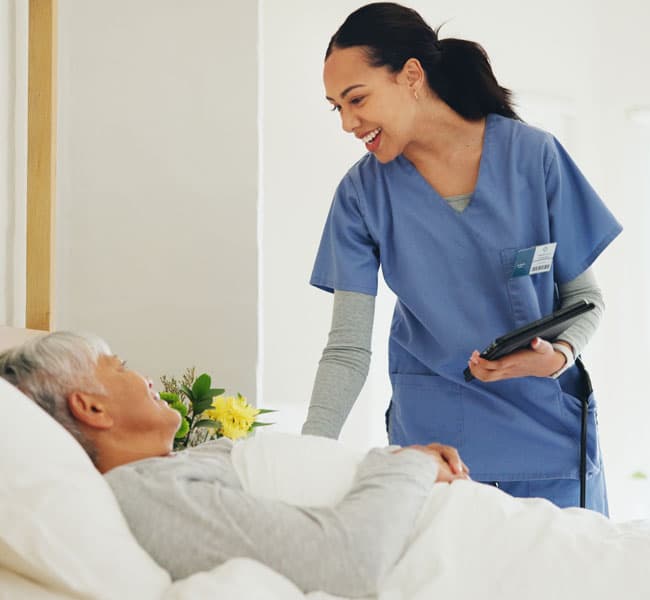 A nurse smiling at a patient in a bed